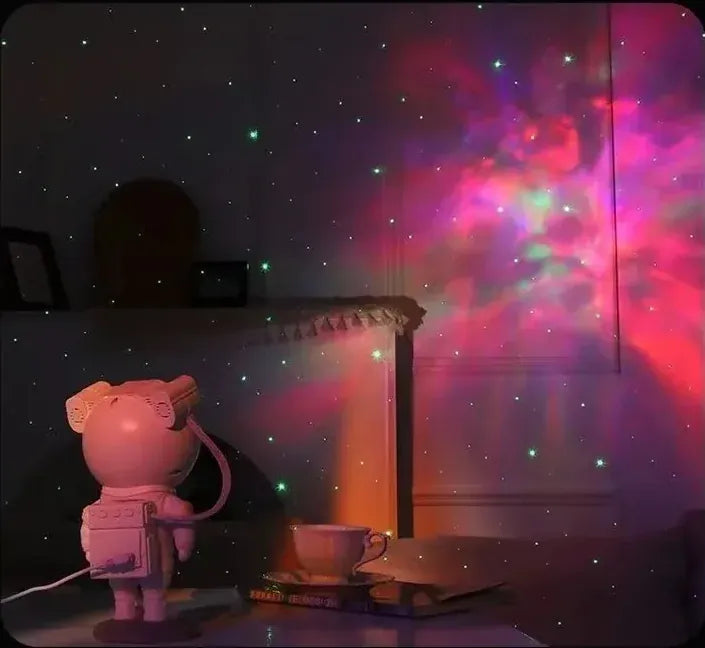Astronaut Galaxy Projector on a table projecting a pink and red nebula across the wall (supplier photo)